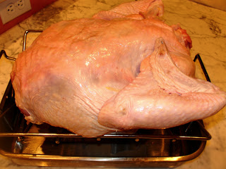 turkey breast side down on a roasting pan